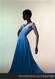 Fashion studio portrait of beautiful woman in azure flowing dress on colorful background. Asian beauty.
