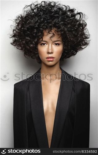 Fashion studio portrait of beautiful woman in black cape with afro curls hairstyle. Fashion and beauty