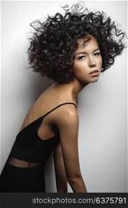 Fashion studio portrait of beautiful woman in black dress with afro curls hairstyle. Fashion and beauty
