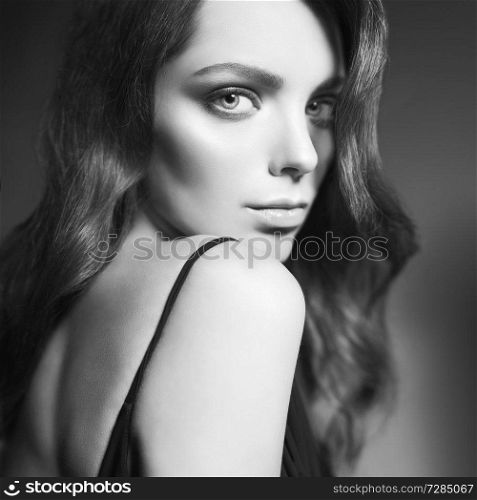 Fashion studio portrait of beautiful young woman. Sexy lady with curly hair in black dress.