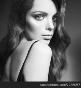 Fashion studio portrait of beautiful young woman. Sexy lady with curly hair in black dress.