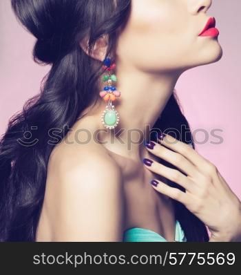 Fashion studio portrait of beautiful young woman with earring. Beauty and manicure. Jewelry and accessories