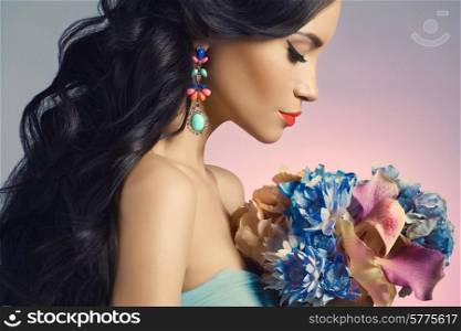 Fashion studio portrait of beautiful young woman with flowers. Jewelry and accessories