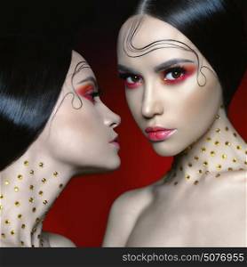 Fashion studio portrait of two beautiful women with bright red makeup. Fashion and Beauty. Perfect makeup