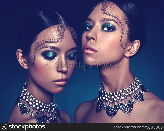 Fashion studio portrait of two twins beautiful asian women with diamond necklace. Fashion and Beauty. Perfect makeup