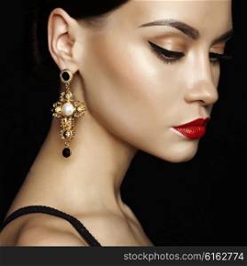 Fashion studio portrait of young beautiful lady with earring on black background