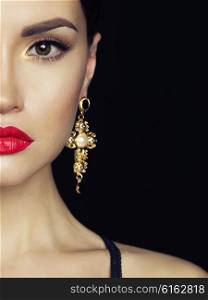 Fashion studio portrait of young beautiful lady with earring on black background