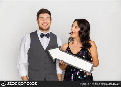 fashion, style and direction concept - happy couple with big arrow at party. happy couple with big arrow at party