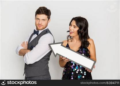 fashion, style and direction concept - happy couple with big arrow at party. happy couple with big arrow at party