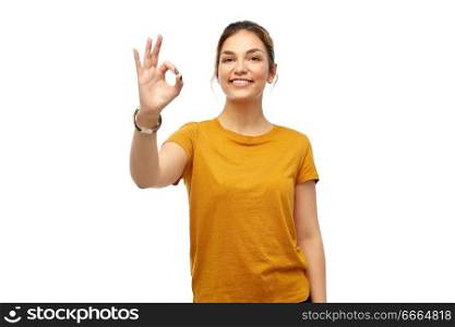 fashion, style and gesture concept - happy smiling young woman or teenage girl over white background showing ok hand sign. happy smiling young woman showing ok hand sign