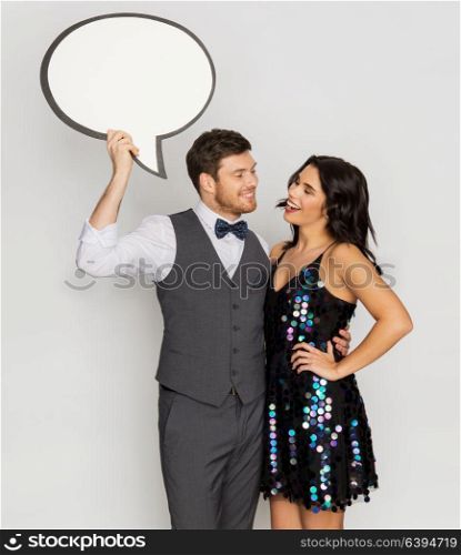 fashion, style and holidays concept - happy couple hugging at party and holding blank text bubble banner. happy couple at party holding text bubble banner