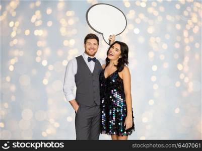 fashion, style and holidays concept - happy couple hugging at party and holding blank text bubble banner over festive lights background. happy couple at party holding text bubble banner