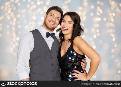 fashion, style and holidays concept - happy couple hugging at party over festive lights background. happy couple hugging at party