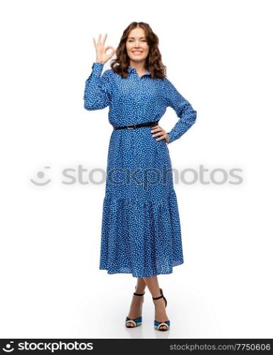 fashion, style and people concept - happy smiling beautiful young woman posing in blue dress showing ok gesture over white background. happy young woman in blue dress showing ok gesture