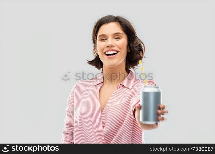 fashion, style and people concept - happy smiling young woman in striped shirt drinking soda from can with paper straw over grey background. woman drinking soda from can with paper straw