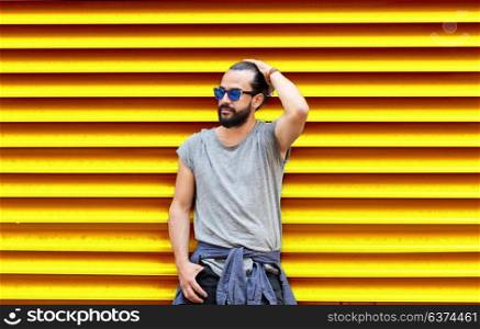 fashion, style and people concept - man in sunglasses with beard over ribbed yellow wall background. man in sunglasses over ribbed yellow background