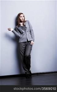 Fashion style. Beautiful female in grey suit posing in studio