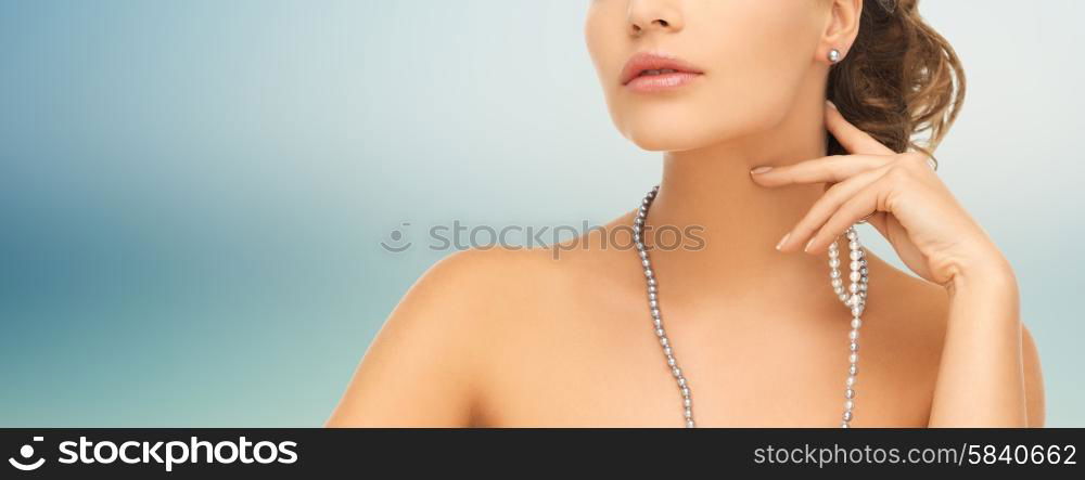 fashion, style, jewelry, beauty and people concept - beautiful woman wearing pearl earrings and necklace over blue background