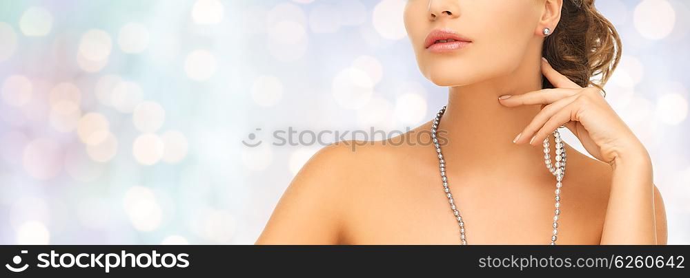 fashion, style, jewelry, beauty and people concept - beautiful woman wearing pearl earrings and necklace over blue holidays lights background