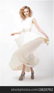 Fashion style - luxurious young woman in light flying dress posing in studio. Series of photos