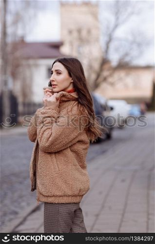 Fashion style portrait. beautiful stylish girl with long hair walks in the city. Portrait of attractive girl on the street. Spring or fall day. selective focus. Fashion style portrait. beautiful stylish girl with long hair walks in the city. Portrait of attractive girl on the street. Spring or fall day. selective focus.