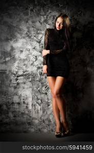 Fashion style portrait of young girl on grey rough wall background