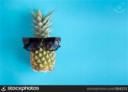 fashion summer pineapple in black sunglasses on blue background . pineapple for summer vacation and party concept.