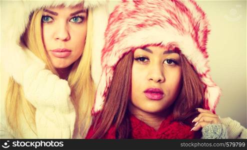 Fashion winter people concept. Two girls with winter outfit. Attractive women wearing fur caps.. Two girls with winter outfit.