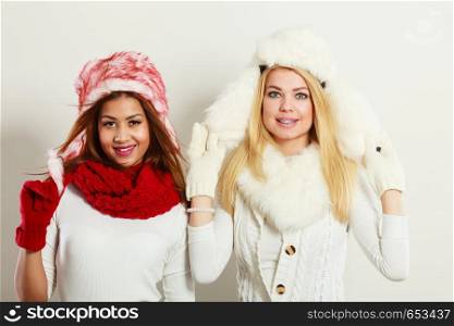 Fashion winter people concept. Two girls with winter outfit. Attractive women wearing fur caps.. Two girls with winter outfit.
