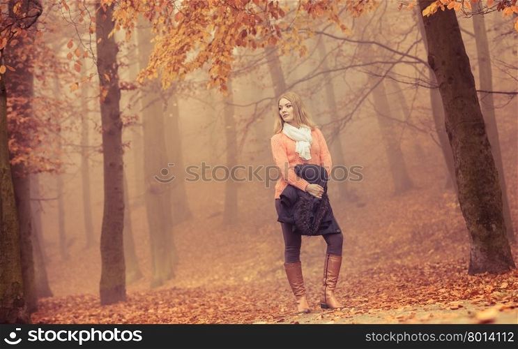 Fashion woman in foggy fall autumn park. Attractive full length young girl holding jacket. Happiness and relax in forest.