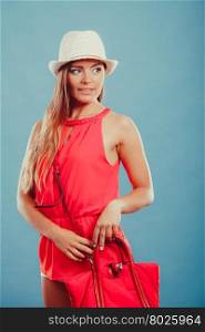 Fashion woman in hat and red shirt with handbag.. Cute attractive young woman girl in red shirt and straw hat with handbag in studio on blue. Summer female fashion vogue.