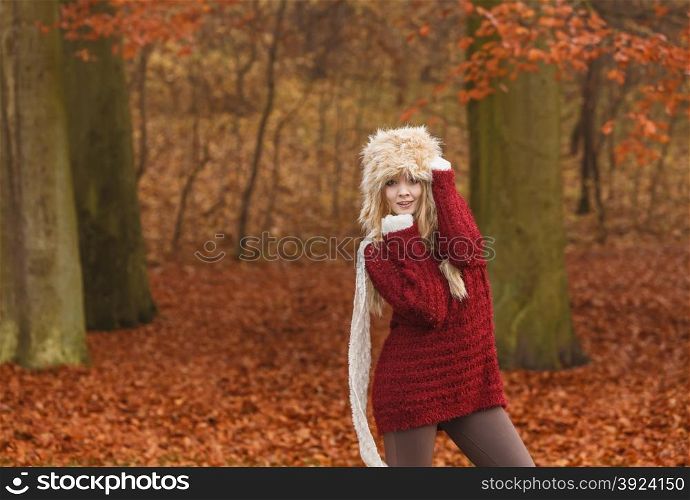 Fashion woman in windy fall autumn park forest.. Fashion woman with flying scarf in windy fall autumn park forest against blowing wind. Young girl posing in fur cap and sweater having fun outdoor.