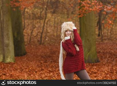 Fashion woman in windy fall autumn park forest.. Fashion woman with flying scarf in windy fall autumn park forest against blowing wind. Young girl posing in fur cap and sweater having fun outdoor.