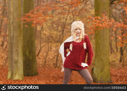 Fashion woman in windy fall autumn park forest.. Joyful fashion woman with flying scarf in windy fall autumn park forest against blowing wind. Young girl in fur cap and sweater having fun outdoor.