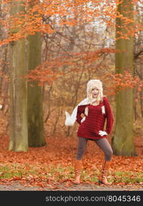 Fashion woman in windy fall autumn park forest.. Joyful fashion woman with flying scarf in windy fall autumn park forest against blowing wind. Young girl in fur cap and sweater having fun outdoor.