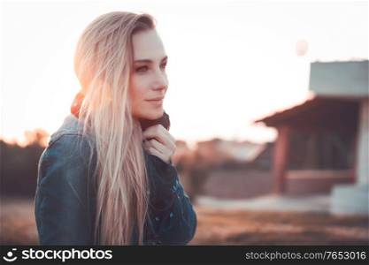 Fashion woman portrait, beautiful blond girl outdoors in sunset light, autumn style, urban life of young people