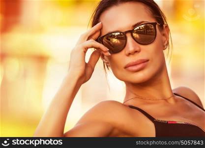 Fashion woman portrait, beautiful girl wearing stylish sunglasses on the beach in bright sunny day, summer vacation look