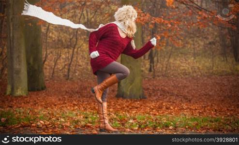 Fashion woman running in fall autumn park forest.. Fashion woman with flying scarf running in fall autumn park forest against blowing wind. Young girl in fur cap and sweater having fun outdoor.