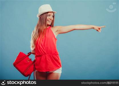 Fashion woman showing blank empty copyspace.. Smiling cute attractive young woman girl in red shirt and hat in studio on blue showing blank empty copyspace. Summer female fashion and advertisement.