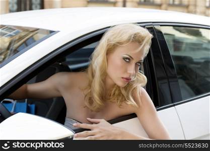 fashion woman with blonde hair and sexy style driving sport car with shopping bags near