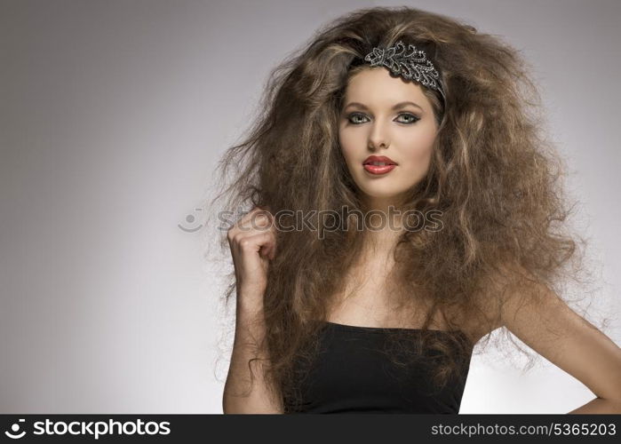 fashion woman with long brown curly hair style posing with pretty make-up and glitter accessory in the hair