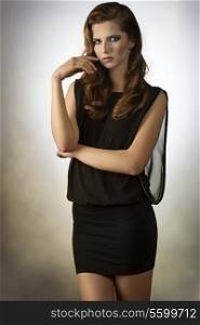fashion woman with sensual eyes wearing elegant black dress, posing with cute stylish make-up and long hair
