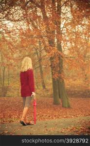 Fashion woman with umbrella relaxing in fall park.. Fashion woman girl in maroon sweater with umbrella walking relaxing in fall autumn park. Relax in forest.