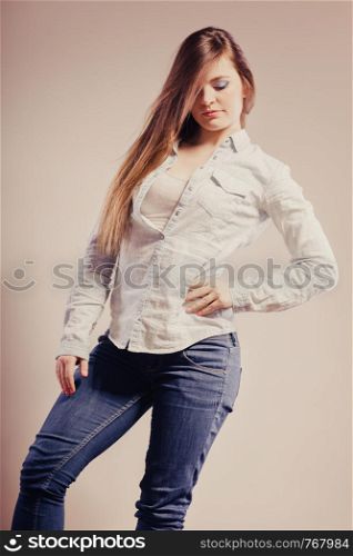 Fashion. Young long hair fashionable woman jeans pants shirt. Female model posing filtered photo