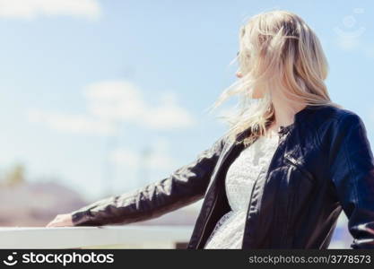 Fashionable beautiful young blond wearing a leather jacket, warm sunny day