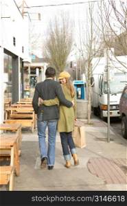 Fashionable Caucasian Girl Walking Along An Urban Sidewalk With Her Boyfriend