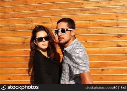 Fashionable couple posing against the wooden wall