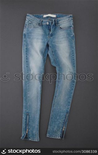 fashionable denim pants on grey background, top view. jeans on grey background
