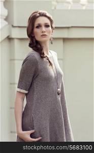 fashionable elegant woman wearing gray dress and stylish jewellery, posing with braid hair-style in outdoor fashion shoot