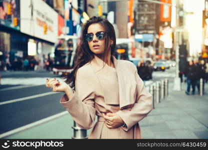 Fashionable girl walking on New York City street in Midtown wearing sunglasses and ping jacket.